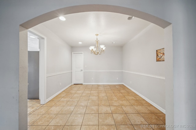 spare room featuring light tile patterned floors and an inviting chandelier