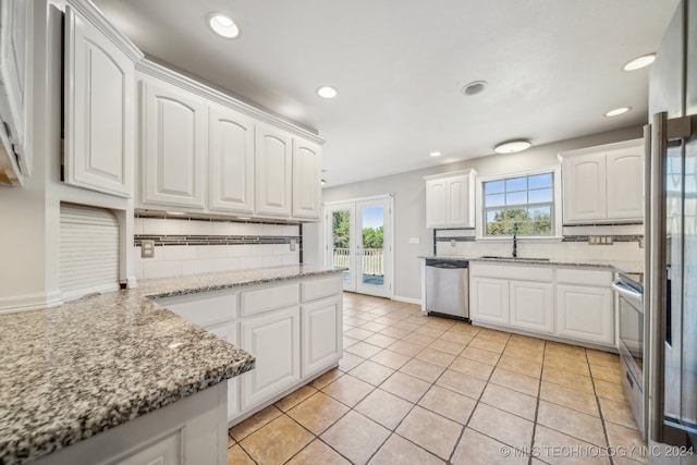 kitchen featuring light stone countertops, appliances with stainless steel finishes, backsplash, and white cabinetry