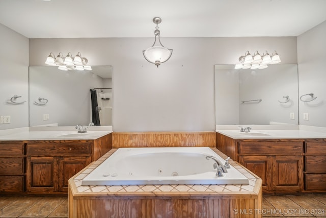 bathroom with tile patterned flooring, vanity, and tiled bath