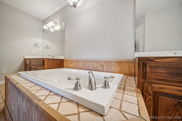 bathroom with a washtub, vanity, and tile patterned flooring