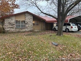 view of side of property featuring a carport and a lawn