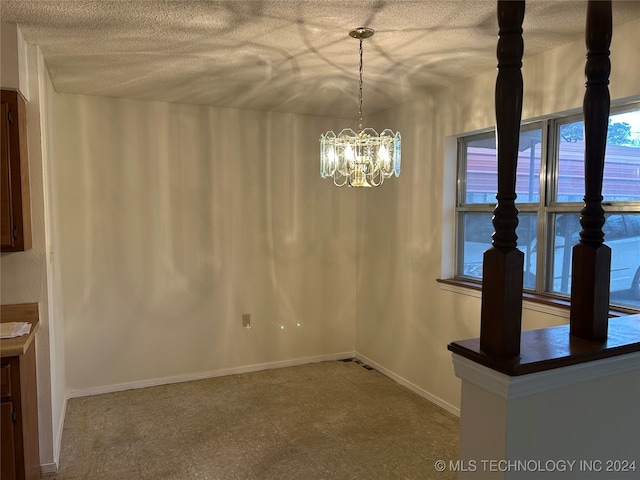 unfurnished dining area with a textured ceiling and a notable chandelier