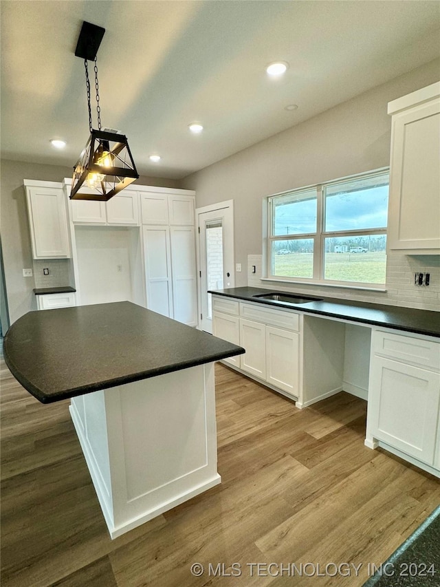 kitchen featuring pendant lighting, a center island, tasteful backsplash, light hardwood / wood-style floors, and white cabinetry