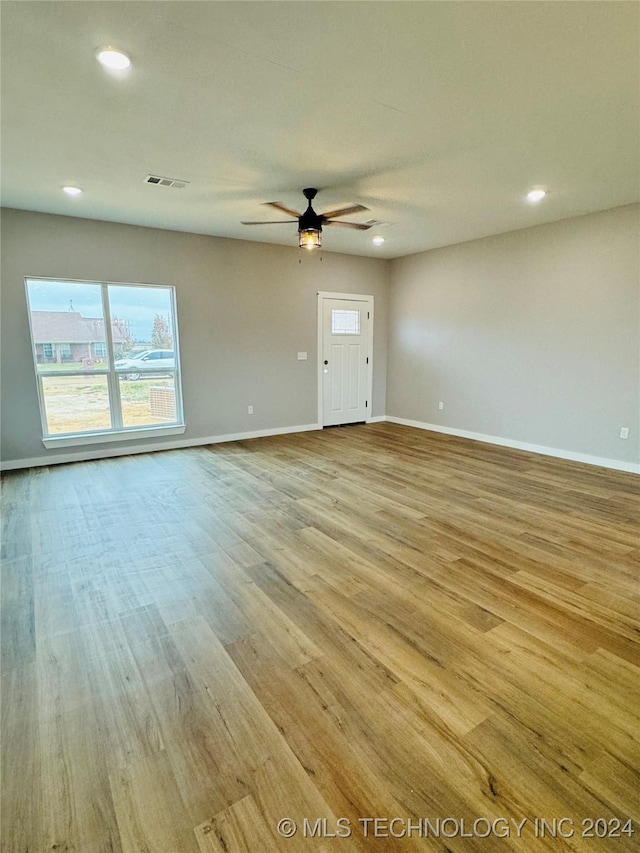 empty room with ceiling fan and light hardwood / wood-style flooring