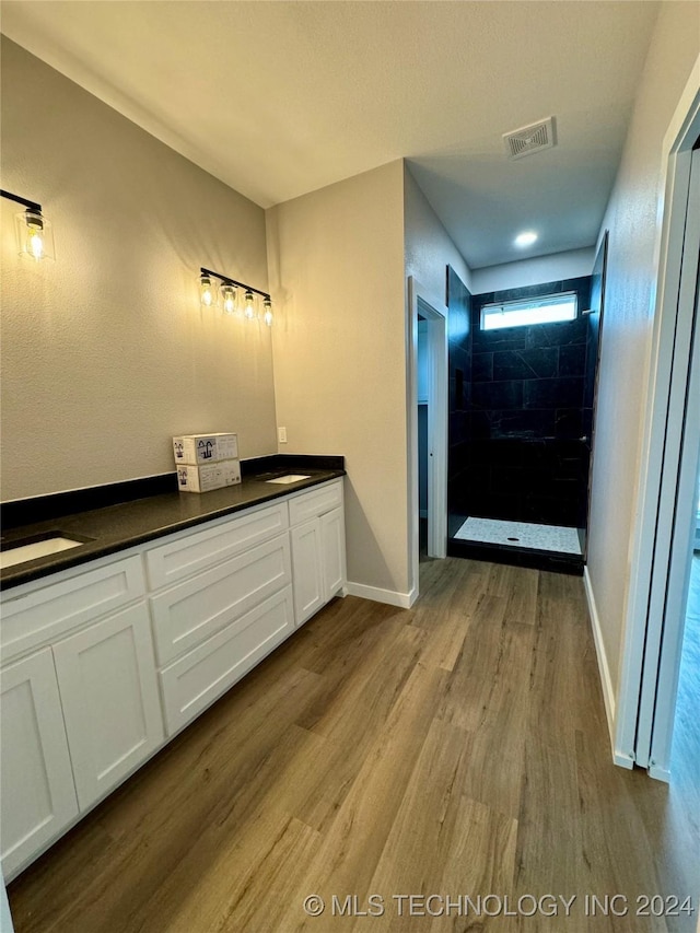 bathroom featuring tiled shower, vanity, and hardwood / wood-style flooring