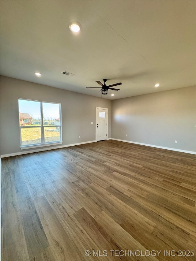 spare room featuring a ceiling fan, dark wood-style floors, visible vents, and baseboards