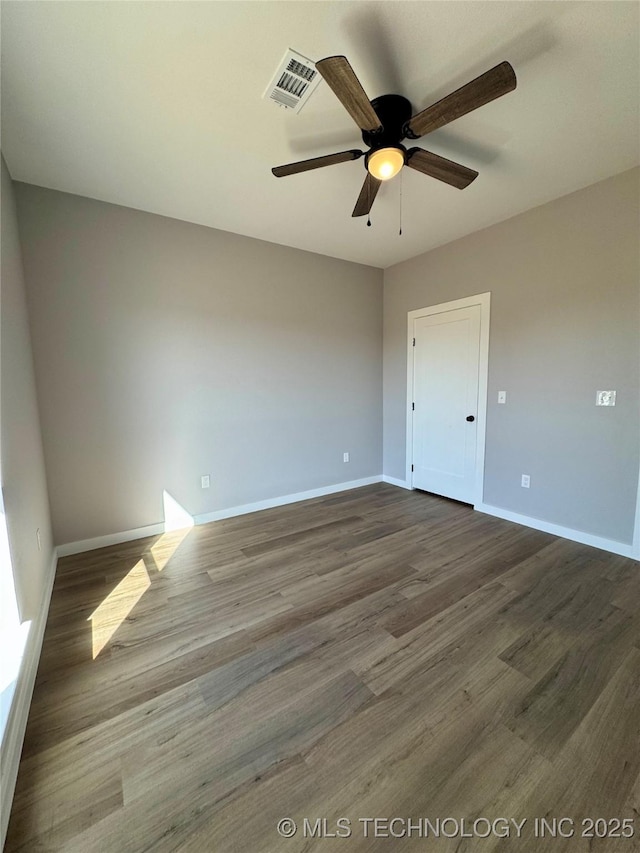 unfurnished room with dark wood finished floors, visible vents, baseboards, and a ceiling fan