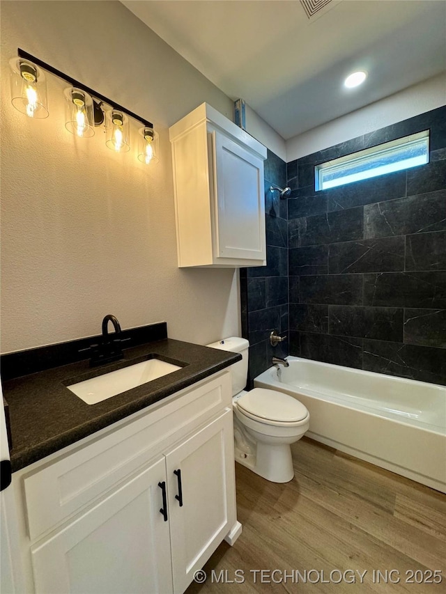 bathroom featuring toilet, vanity,  shower combination, and wood finished floors