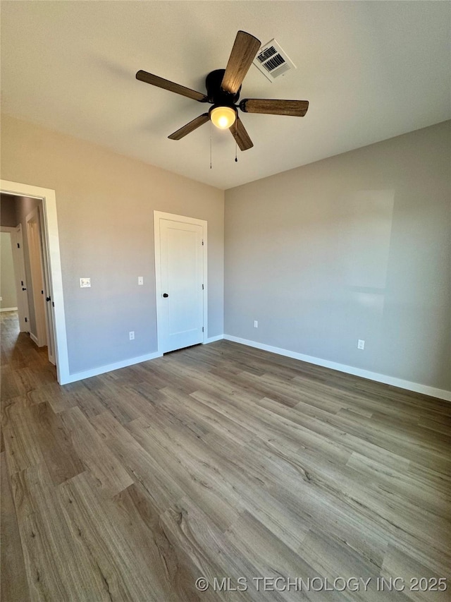 unfurnished bedroom with a ceiling fan, wood finished floors, visible vents, and baseboards