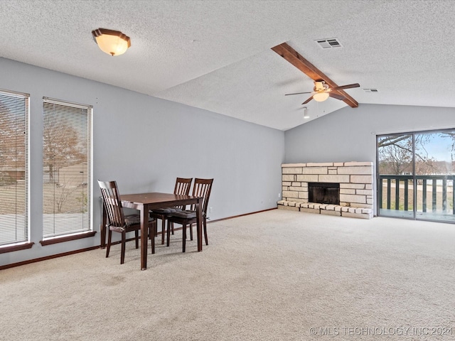 carpeted dining space with ceiling fan, a fireplace, lofted ceiling with beams, and a textured ceiling