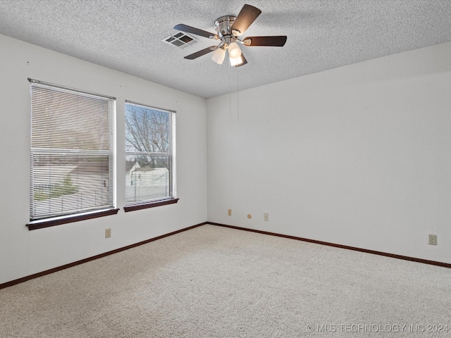 carpeted spare room with a textured ceiling, a wealth of natural light, and ceiling fan