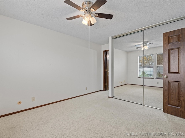 unfurnished bedroom with light carpet, a textured ceiling, a closet, and ceiling fan