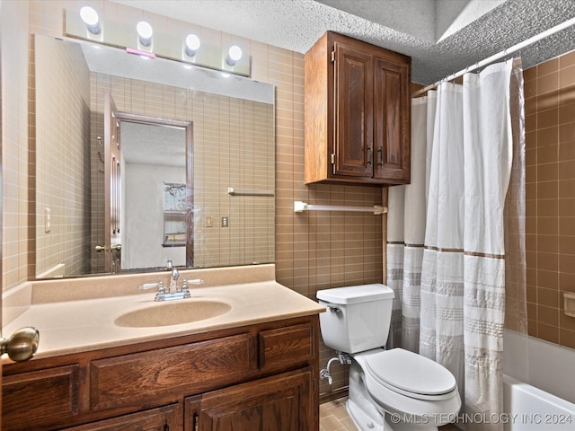 full bathroom with vanity, toilet, a textured ceiling, tile walls, and shower / tub combo