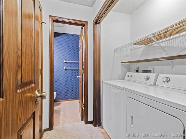 laundry room featuring light tile patterned floors, a textured ceiling, and washing machine and clothes dryer