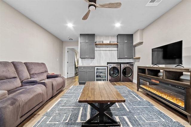 living room with wine cooler, light hardwood / wood-style flooring, washer and clothes dryer, and ceiling fan