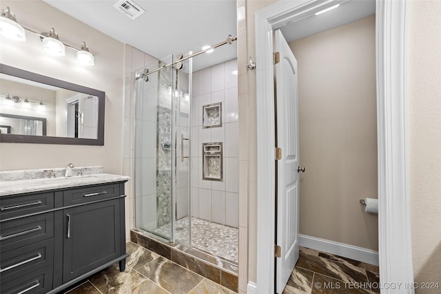 bathroom featuring a shower with door and vanity