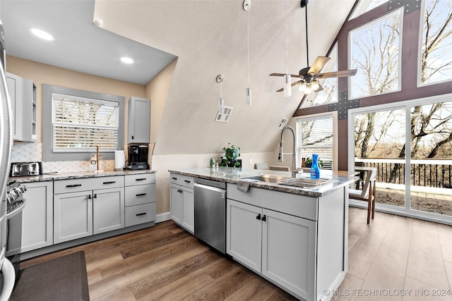 kitchen with hardwood / wood-style floors, stainless steel appliances, light stone counters, and plenty of natural light