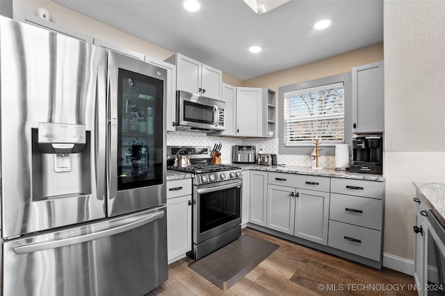 kitchen featuring backsplash, light stone countertops, dark hardwood / wood-style flooring, and stainless steel appliances