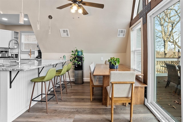 dining space featuring ceiling fan, hardwood / wood-style floors, a healthy amount of sunlight, and vaulted ceiling