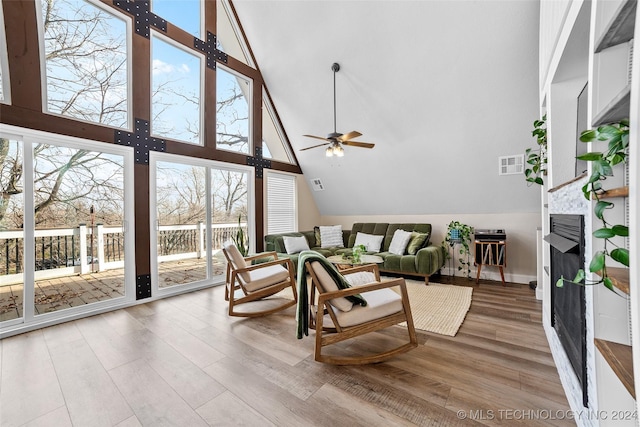 living room with a wealth of natural light, ceiling fan, high vaulted ceiling, and light hardwood / wood-style flooring