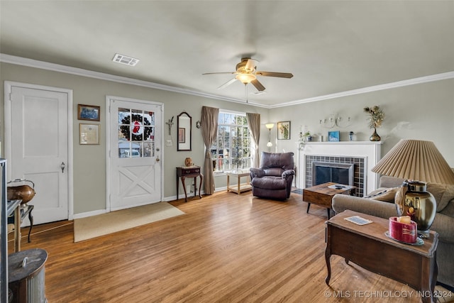 living room with a fireplace, crown molding, light hardwood / wood-style flooring, and ceiling fan