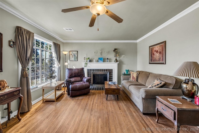 living room with a fireplace, light wood-type flooring, ceiling fan, and crown molding