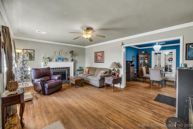 living room with hardwood / wood-style flooring, ceiling fan, a fireplace, and crown molding