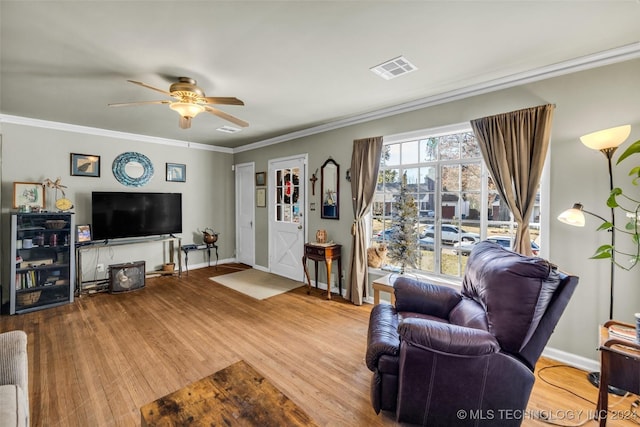 living room with crown molding, ceiling fan, and light wood-type flooring