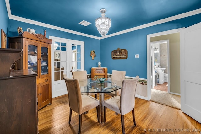 dining room with a chandelier, light hardwood / wood-style floors, and ornamental molding