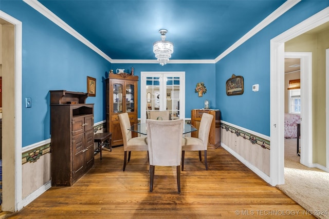 dining space with wood-type flooring, an inviting chandelier, and crown molding