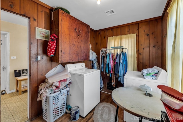 clothes washing area with wooden walls and washer / clothes dryer