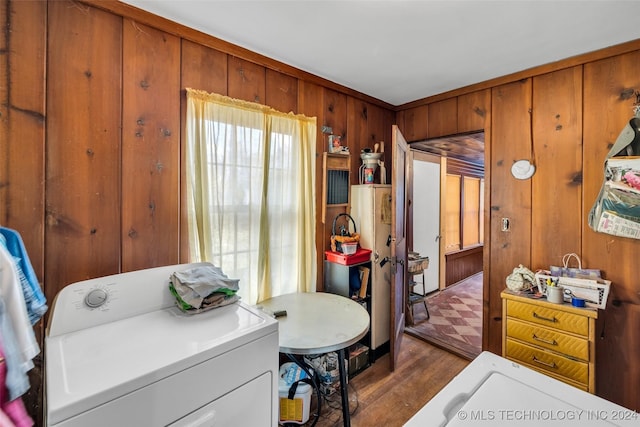 bedroom featuring hardwood / wood-style flooring, wooden walls, and washer / clothes dryer