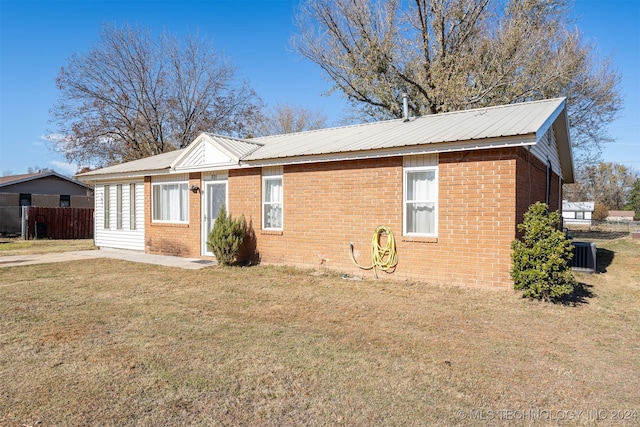 view of side of property with a lawn and central AC