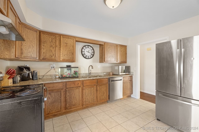 kitchen featuring appliances with stainless steel finishes, light stone counters, sink, range hood, and light tile patterned flooring