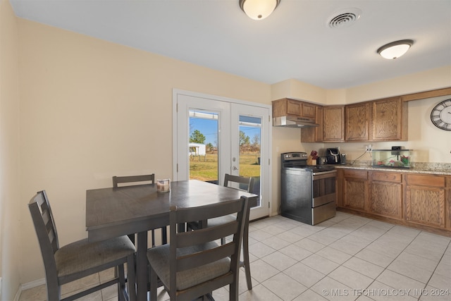 kitchen featuring light stone counters, french doors, light tile patterned flooring, and stainless steel range with electric stovetop