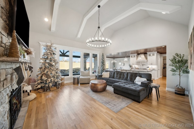 living room featuring light wood-type flooring, an inviting chandelier, high vaulted ceiling, and a stone fireplace