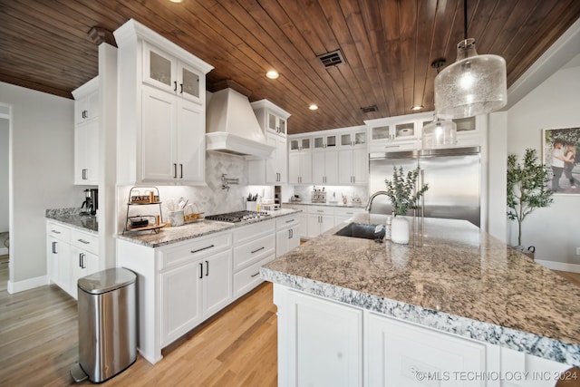 kitchen with pendant lighting, wooden ceiling, white cabinets, custom range hood, and stainless steel appliances