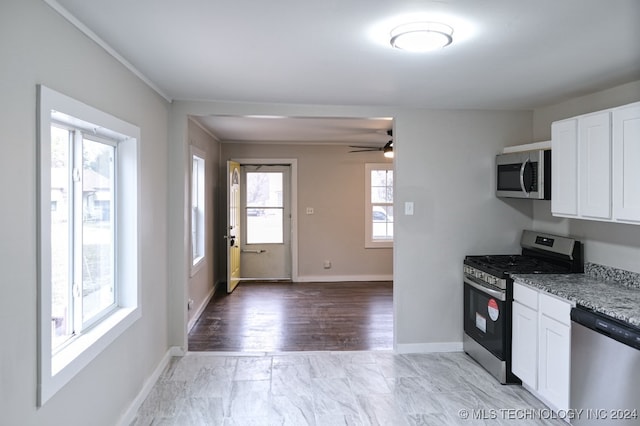 kitchen featuring light stone countertops, light hardwood / wood-style flooring, white cabinets, and appliances with stainless steel finishes