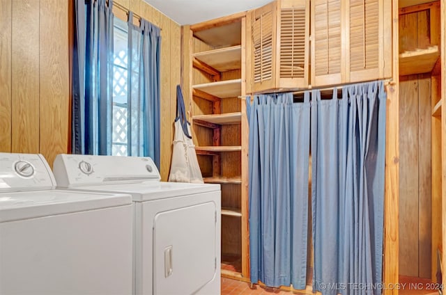 laundry area with wooden walls and washer and clothes dryer