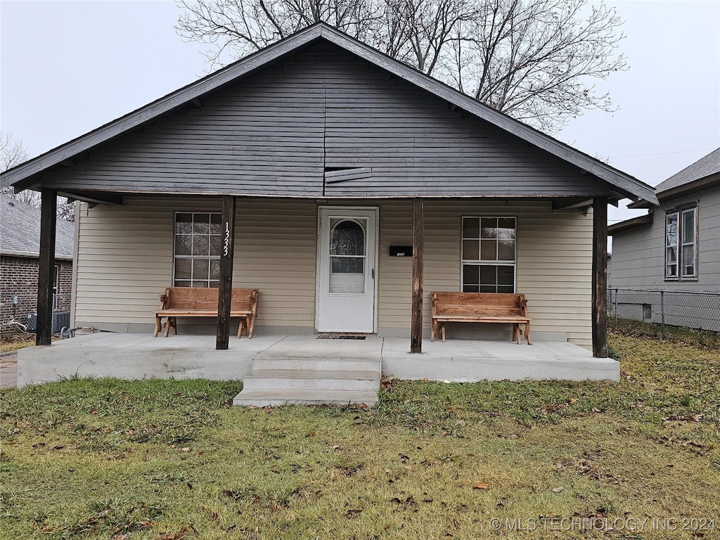 rear view of property featuring a lawn and a porch