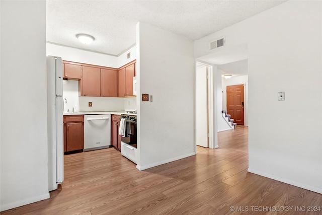 kitchen with a textured ceiling, light hardwood / wood-style flooring, and white appliances