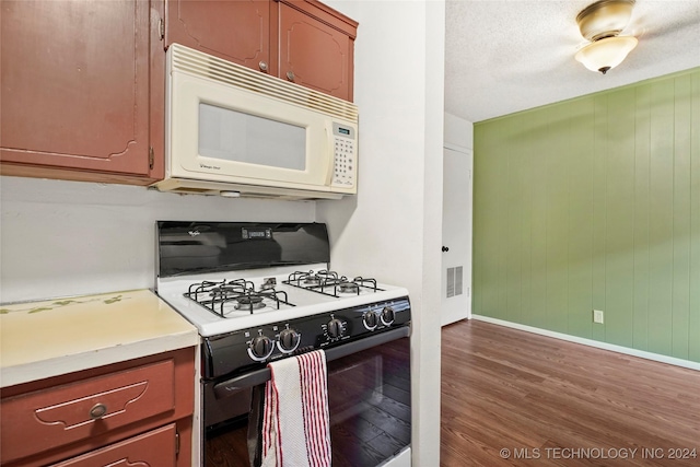 kitchen with a textured ceiling, white appliances, and dark wood-type flooring