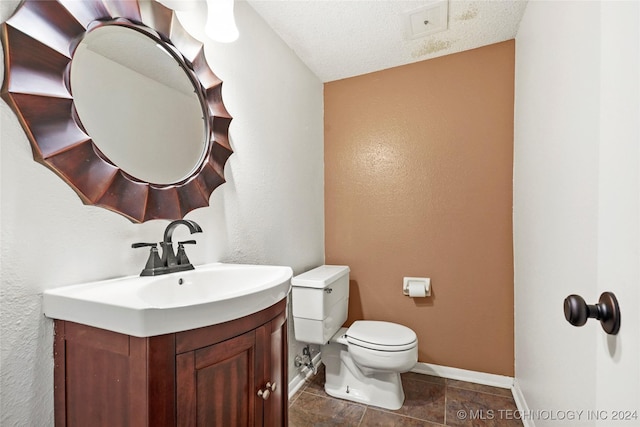 bathroom featuring a textured ceiling, vanity, and toilet