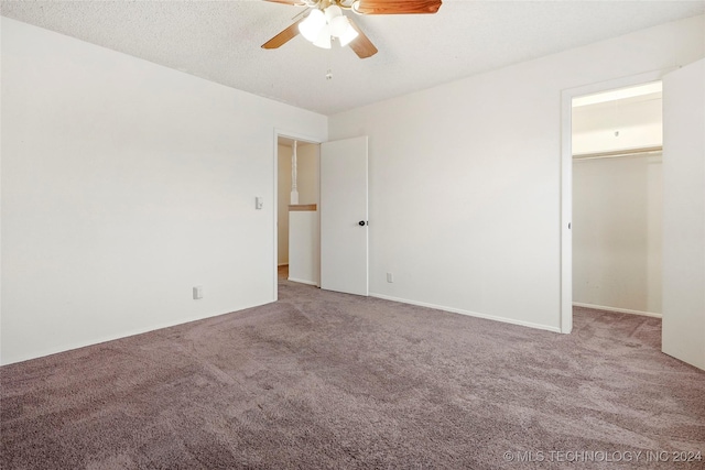 unfurnished bedroom featuring ceiling fan, a closet, carpet floors, and a spacious closet