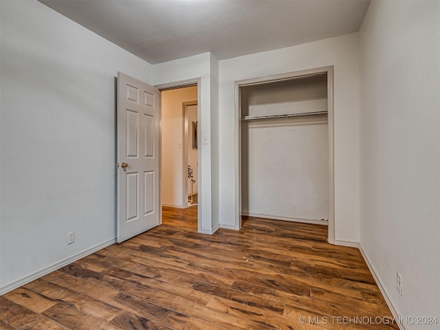 unfurnished bedroom with a closet and dark hardwood / wood-style flooring