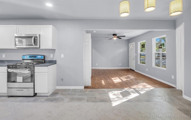 kitchen featuring white cabinets, light hardwood / wood-style floors, stainless steel appliances, and pendant lighting