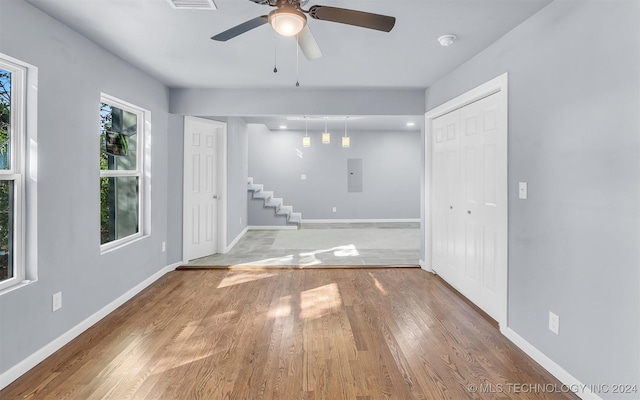 empty room featuring electric panel, ceiling fan, and wood-type flooring