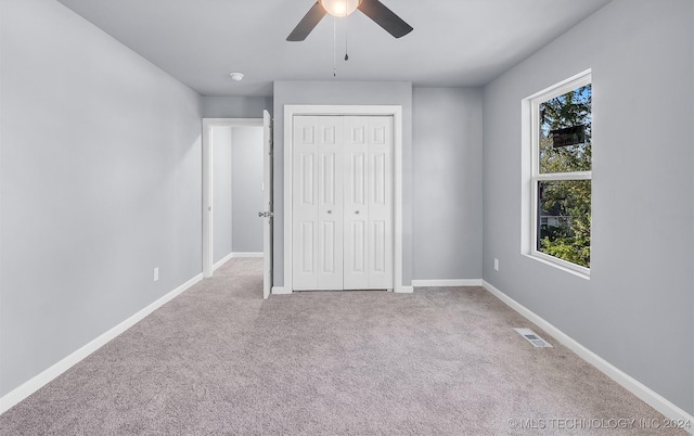 unfurnished bedroom featuring light carpet, a closet, and ceiling fan