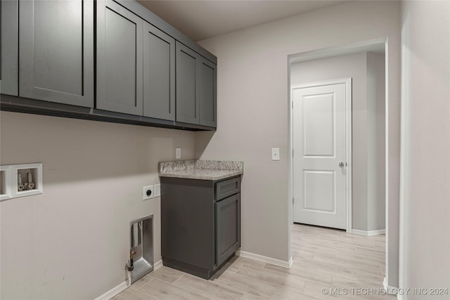 clothes washing area with cabinets, washer hookup, hookup for an electric dryer, gas dryer hookup, and light hardwood / wood-style floors