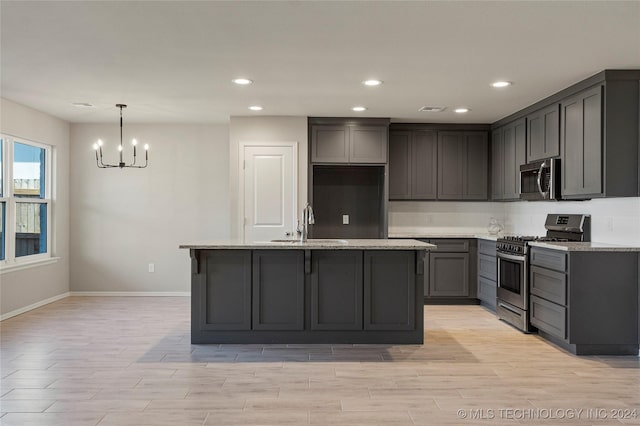 kitchen featuring gray cabinetry, a chandelier, a kitchen island, and stainless steel appliances